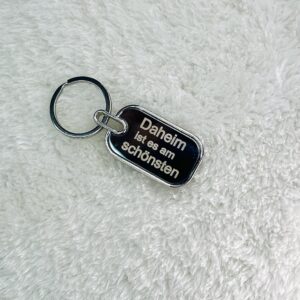 Rechteckiger Metall-Schlüsselanhänger mit abgerundeten Ecken und beispielhafter Lasergravur 'Daheim ist es am schönsten' - hochwertiger Anhänger mit individuellem Wunschtext für Schlüssel, Taschen oder als Geschenk